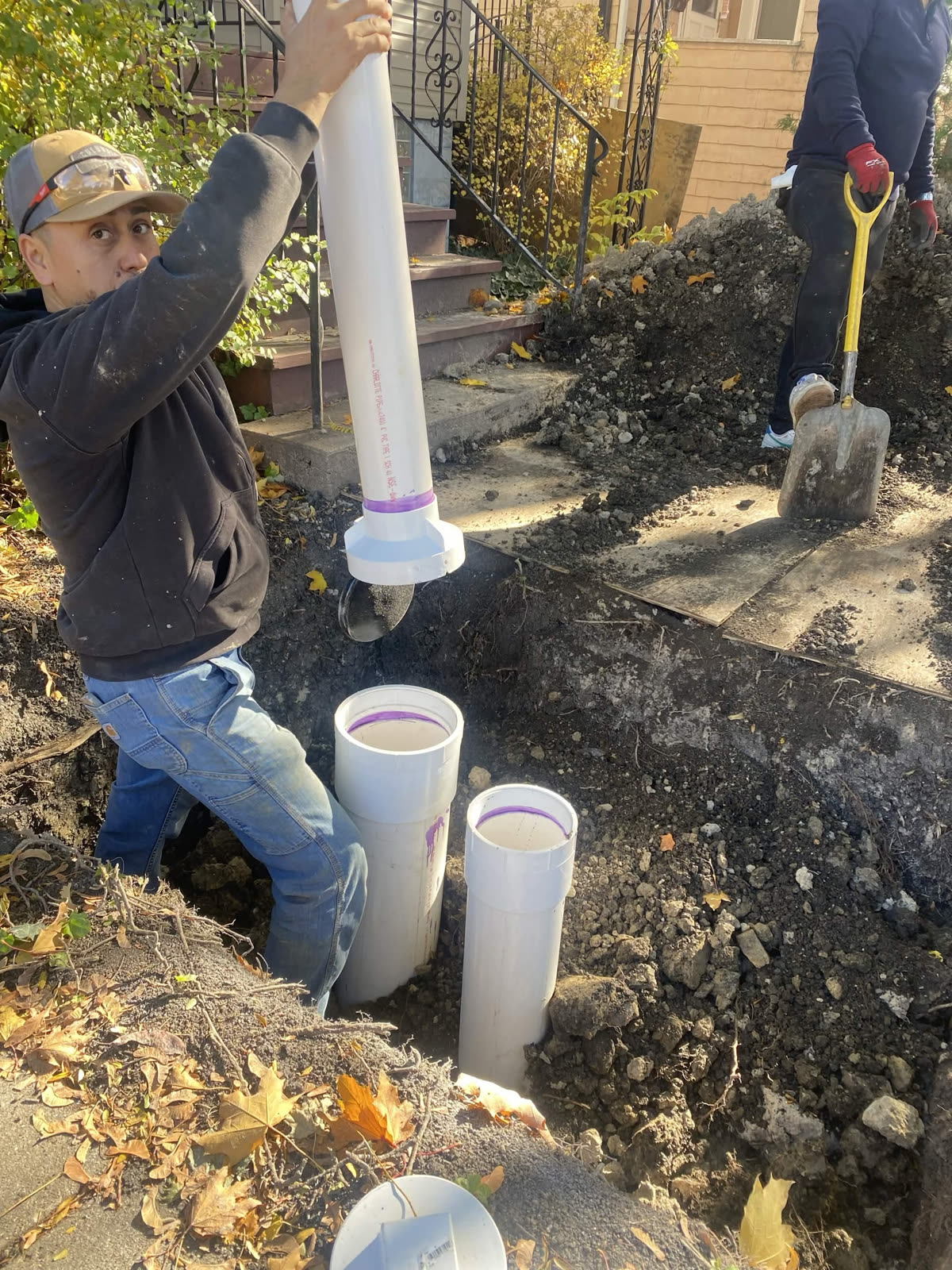 Plumber installing new PVC drain piping outside a home
